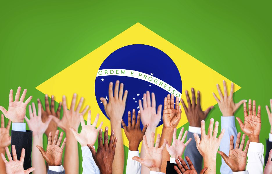 Group of Multi-Ethnic Arms Raised and a Flag of Brazil as a Background votacao brasil bandeira voto participacao