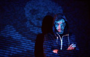 Foto de hacker com projeção de zero e um - Crédito: Divulgação